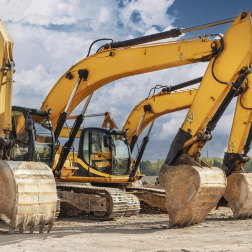 Powerful excavators at a construction site against a blue cloudy sky. Earthmoving construction equipment. Lots of excavators